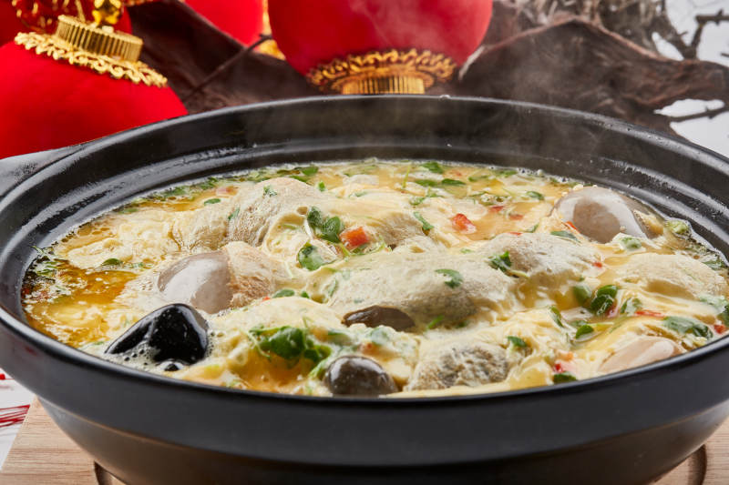 黑色砂锅装的创意美食鸡蛋碰石头