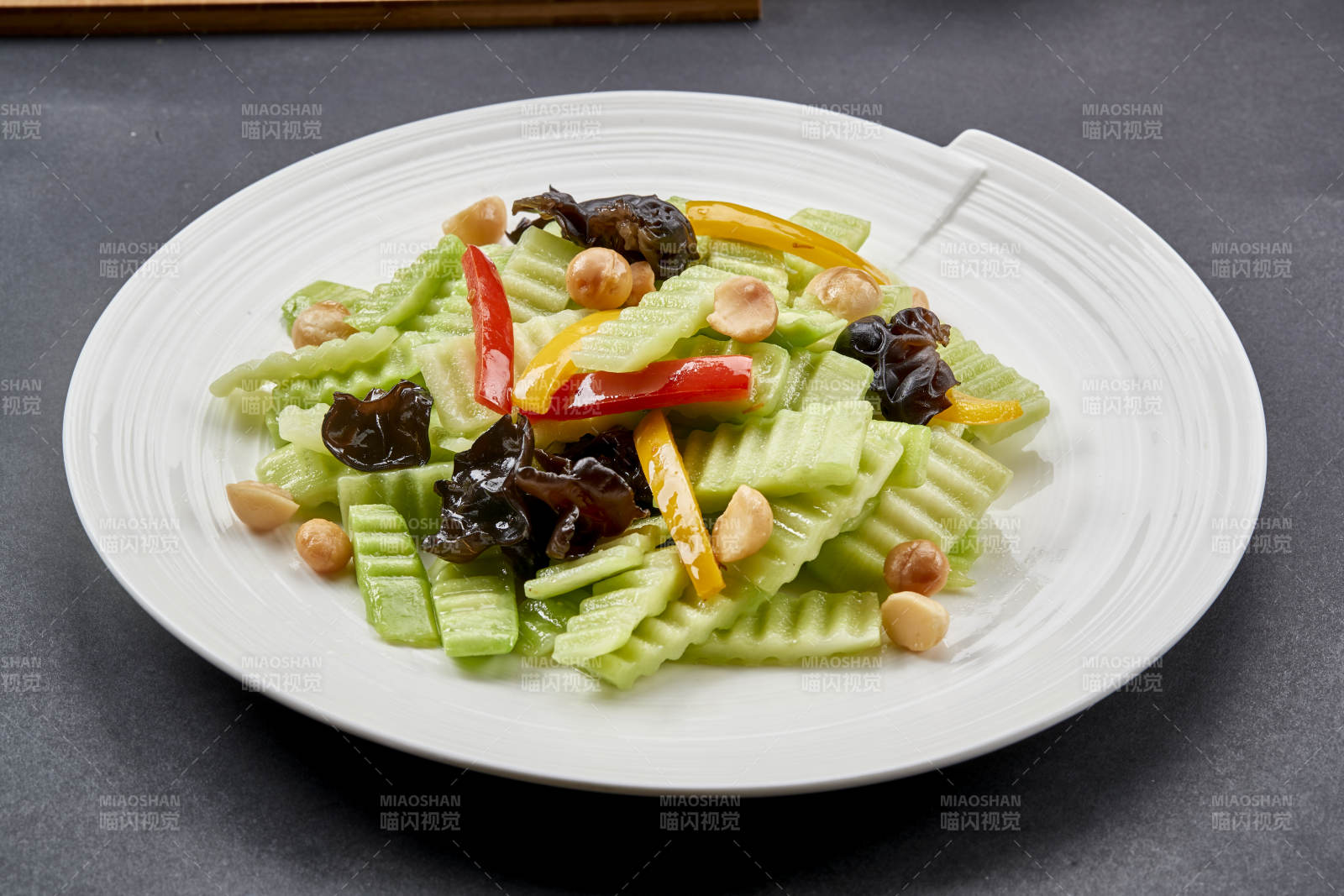 圆瓷盘装的彩椒木耳乳瓜炒银杏-摄影图