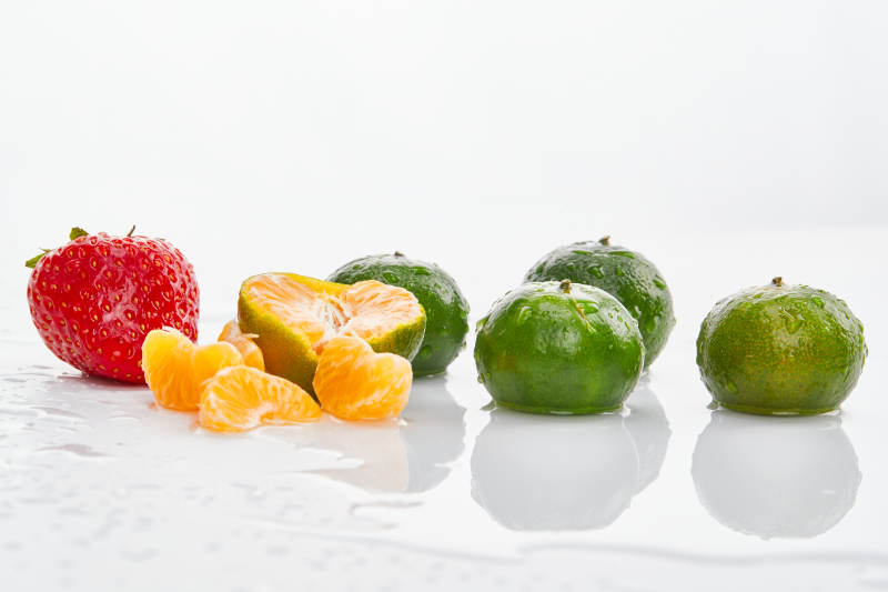 白色背景上摆放的小青柑与草莓