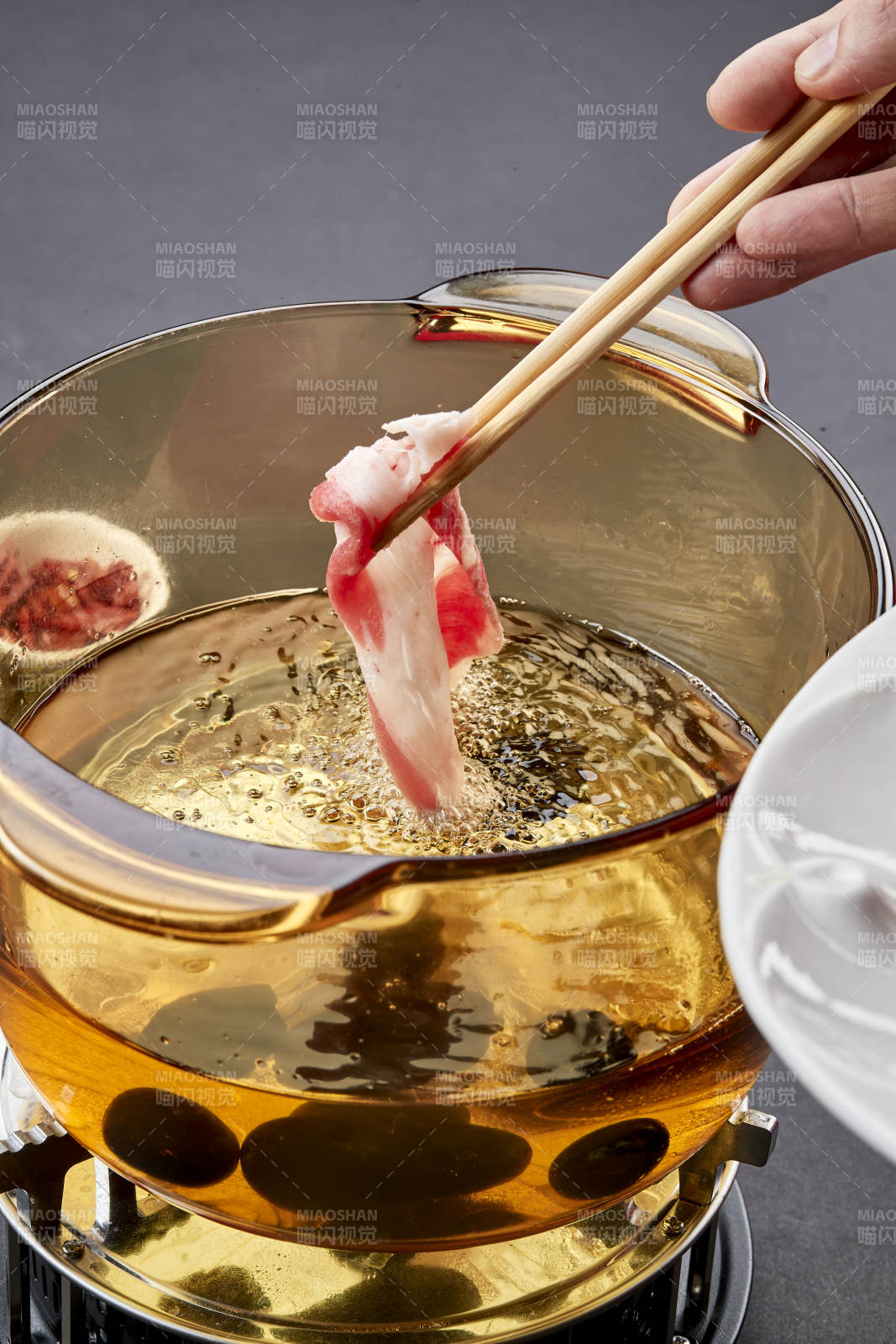 向巖石加熱的沸騰食用油中投放鮮美肥牛片