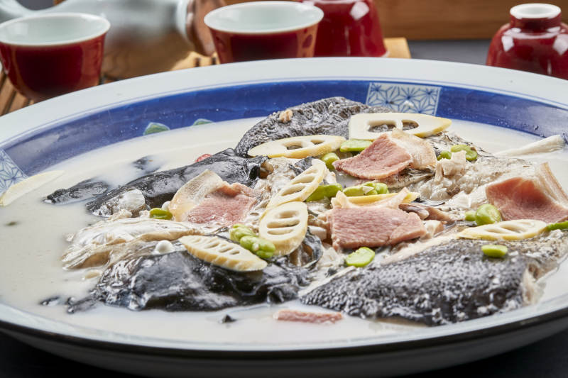 青花瓷盘装的高级奶汤腌笃鲜炖大鲢鱼头