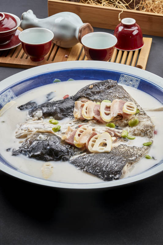 青花瓷盘装的高级奶汤腌笃鲜炖大鲢鱼头