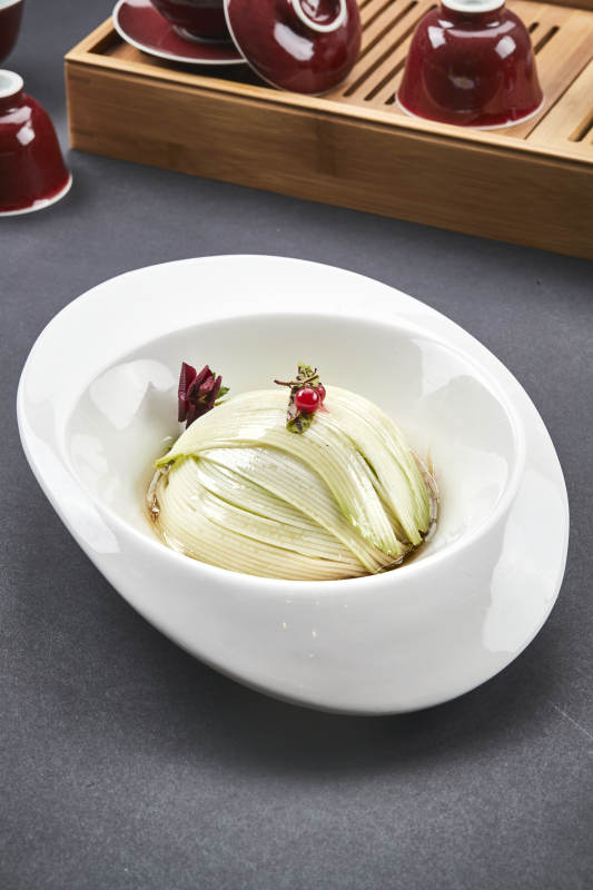 白色椭圆瓷盘装的凉拌浇汁西芹丝