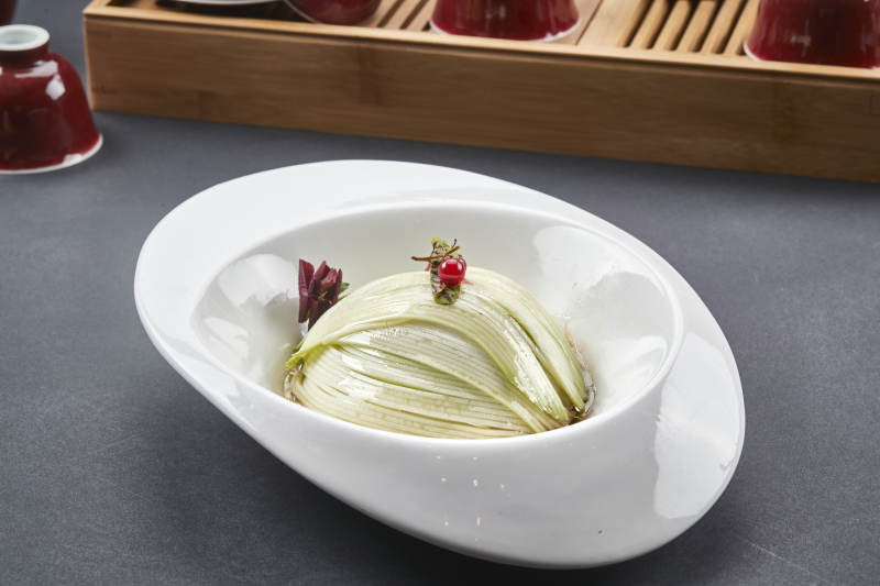 白色椭圆瓷盘装的凉拌浇汁西芹丝