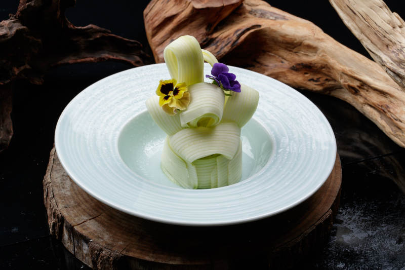 青瓷盤裝的蘸汁西芹絲擺放在樟木砧板上