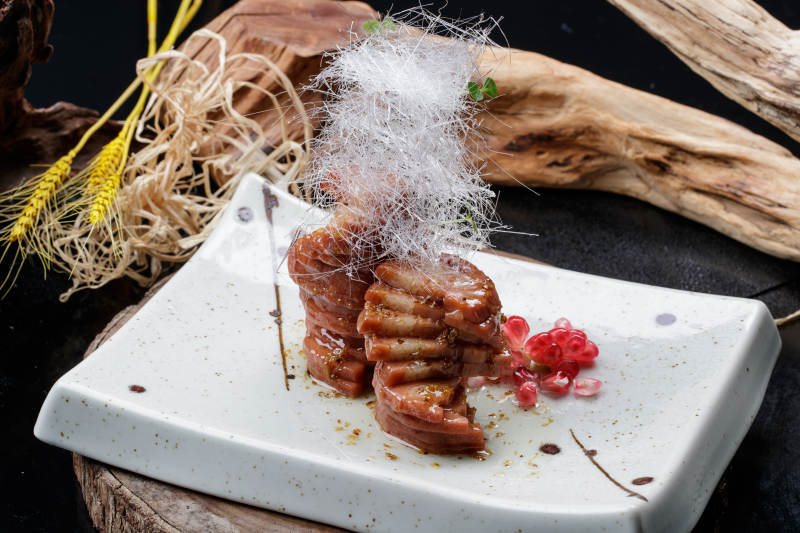 青瓷盘装的糖丝蜂蜜黄米藕摆放在樟木砧板上