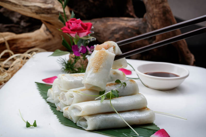 方形瓷盘装的河内肠粉摆放在黑色背景上