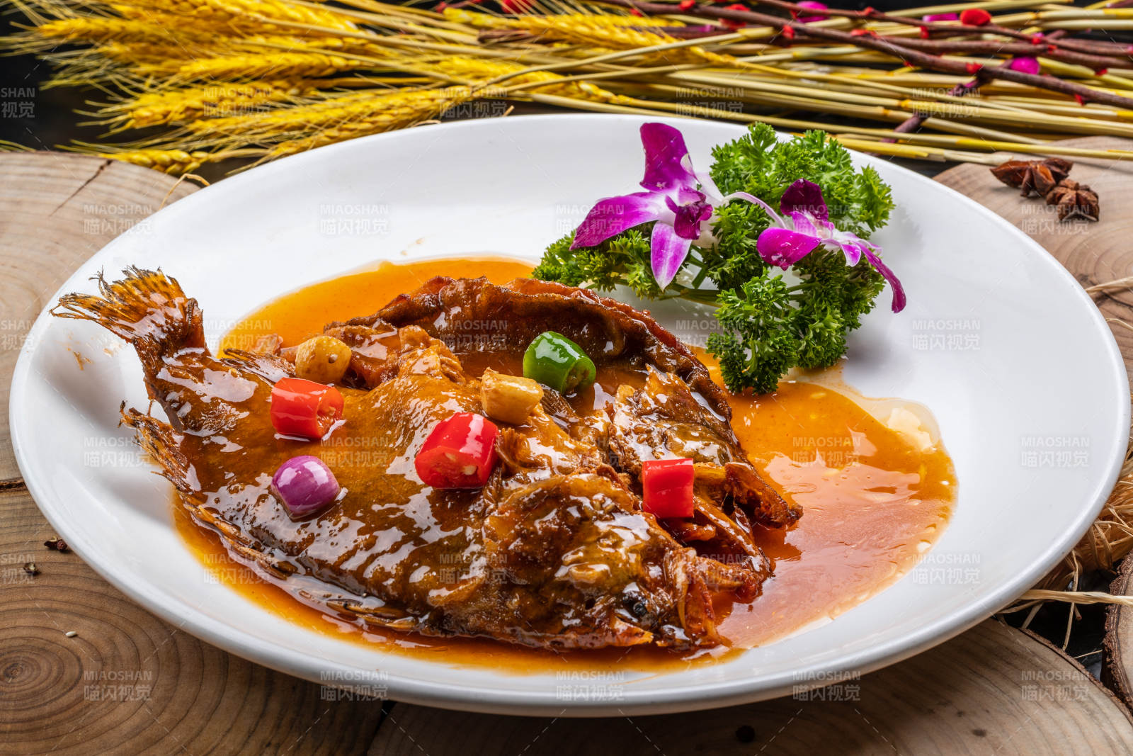 白色圆盘装的红烧罗非鱼摆放在樟木砧板上