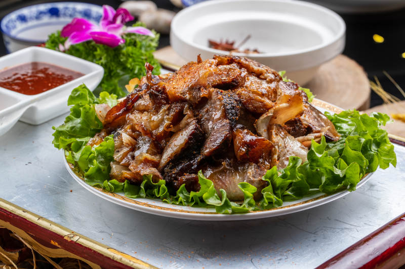 红漆木板装的分切全羊肉摆放在樟木砧板上