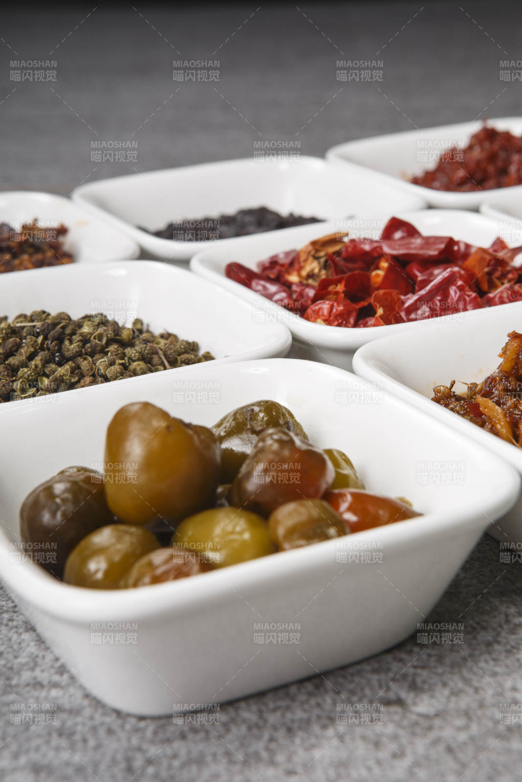 白色方磁盘装的调料摆放在灰色石板