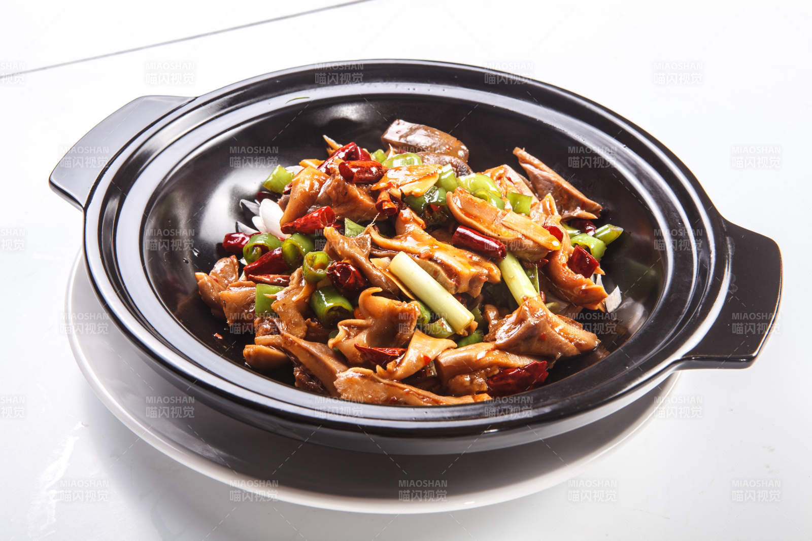白色背景下黑色砂鍋米椒辣豬肚-攝影圖