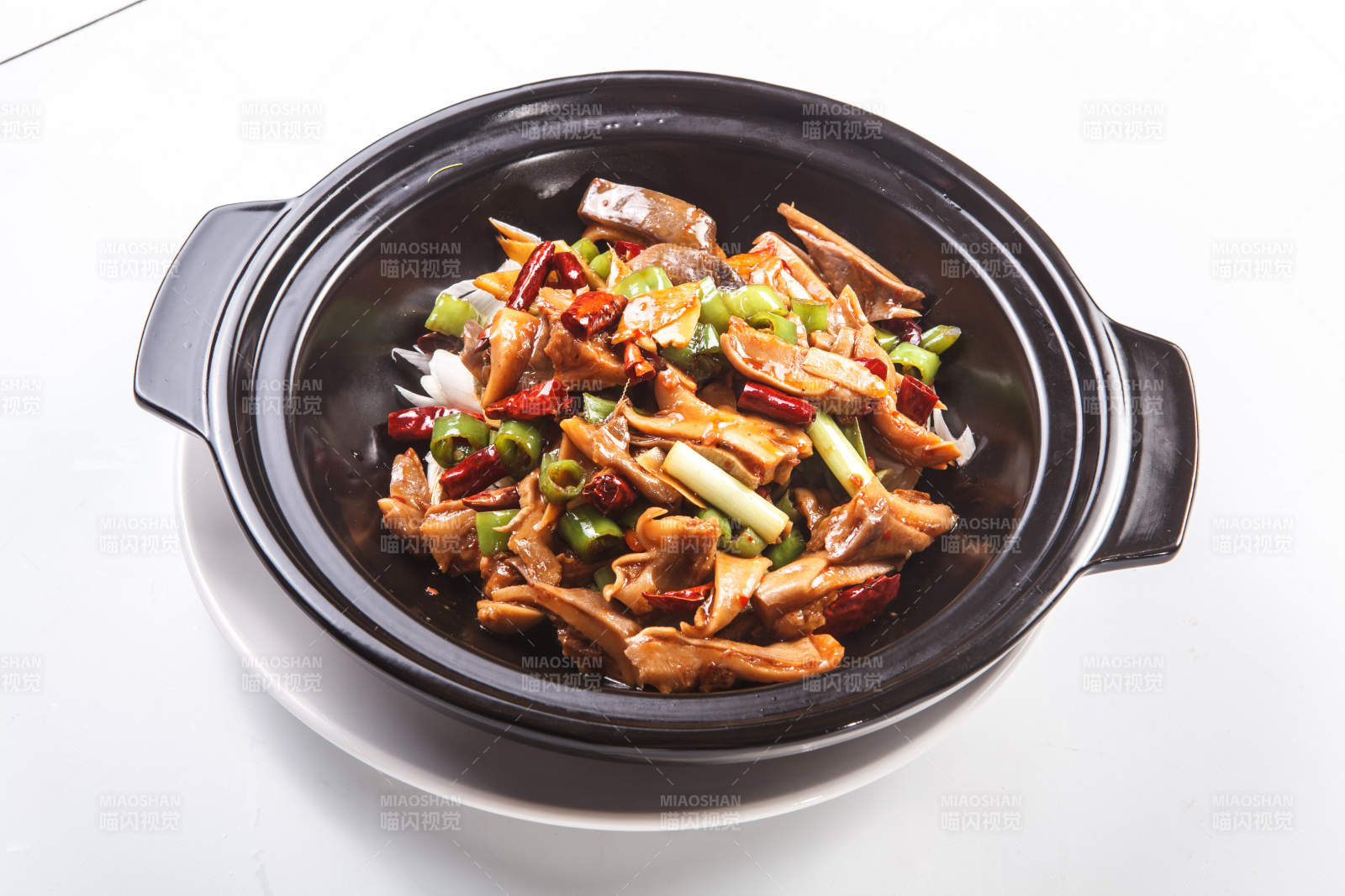 白色背景下黑色砂鍋米椒辣豬肚-攝影圖