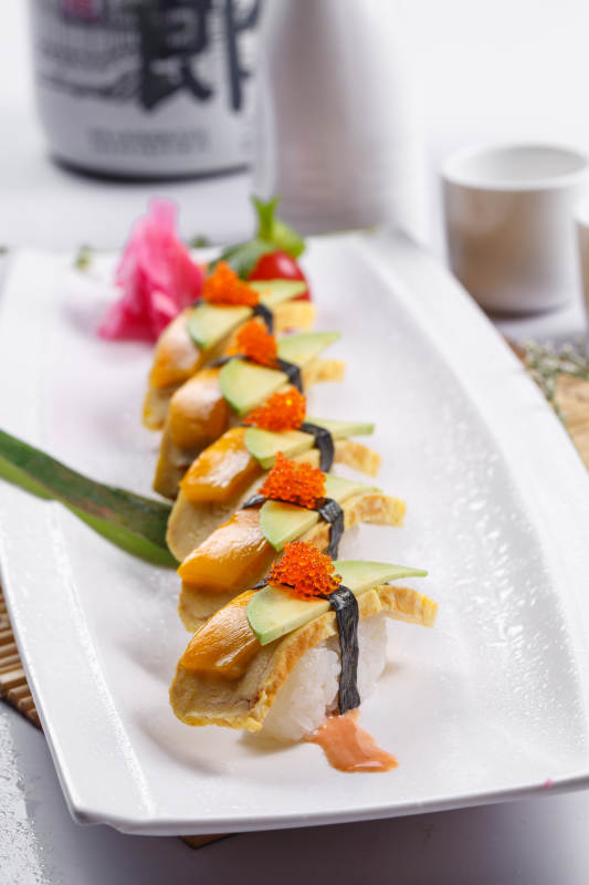 烧蛋蟹子芒果手握寿司摆放在寿司帘上