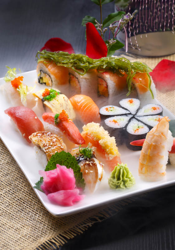 长方形白瓷盘装的豪华寿司拼盘摆放在草垫上
