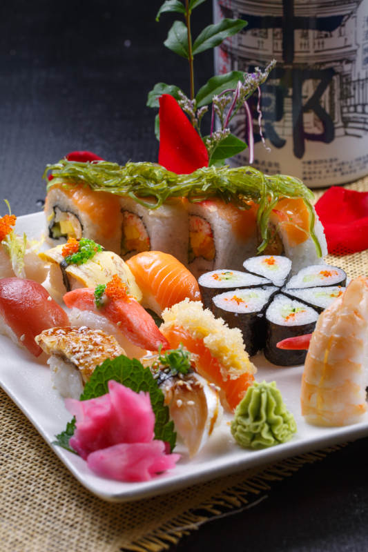 长方形白瓷盘装的豪华寿司拼盘摆放在草垫上