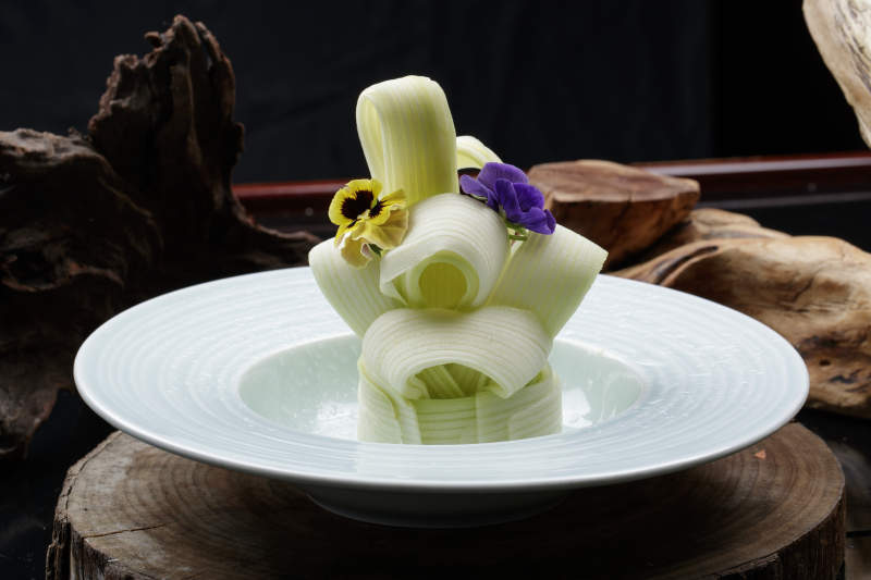 青瓷盤裝的蘸汁西芹絲擺放在樟木砧板上