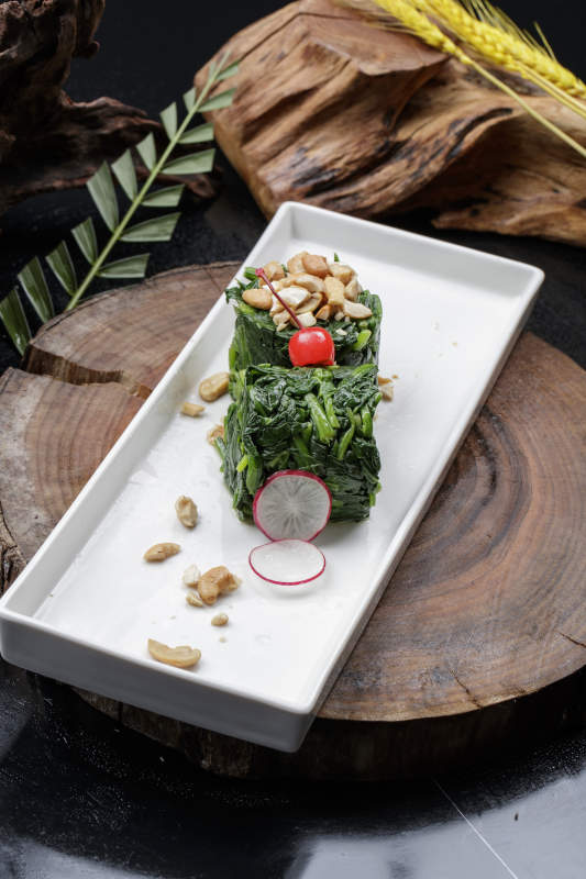 長方形瓷盤裝的菠菜卷擺放在樟木砧板上