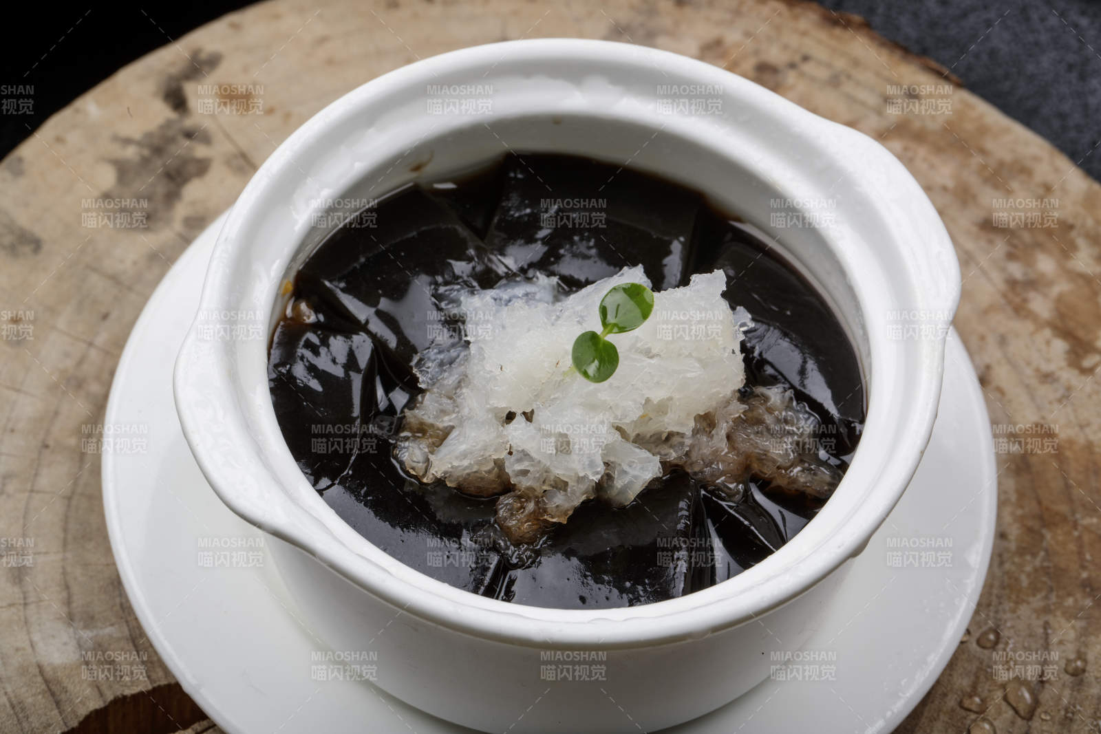 白色汤盅装的银耳龟苓膏摆放在樟木砧板上