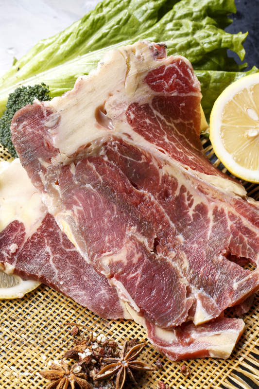 黑色背景草垫上的T骨牛排配柠檬