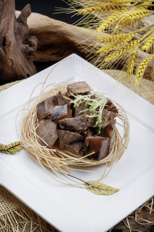 方形瓷盘装的老卤汤牛方粒摆放在麻布垫子上