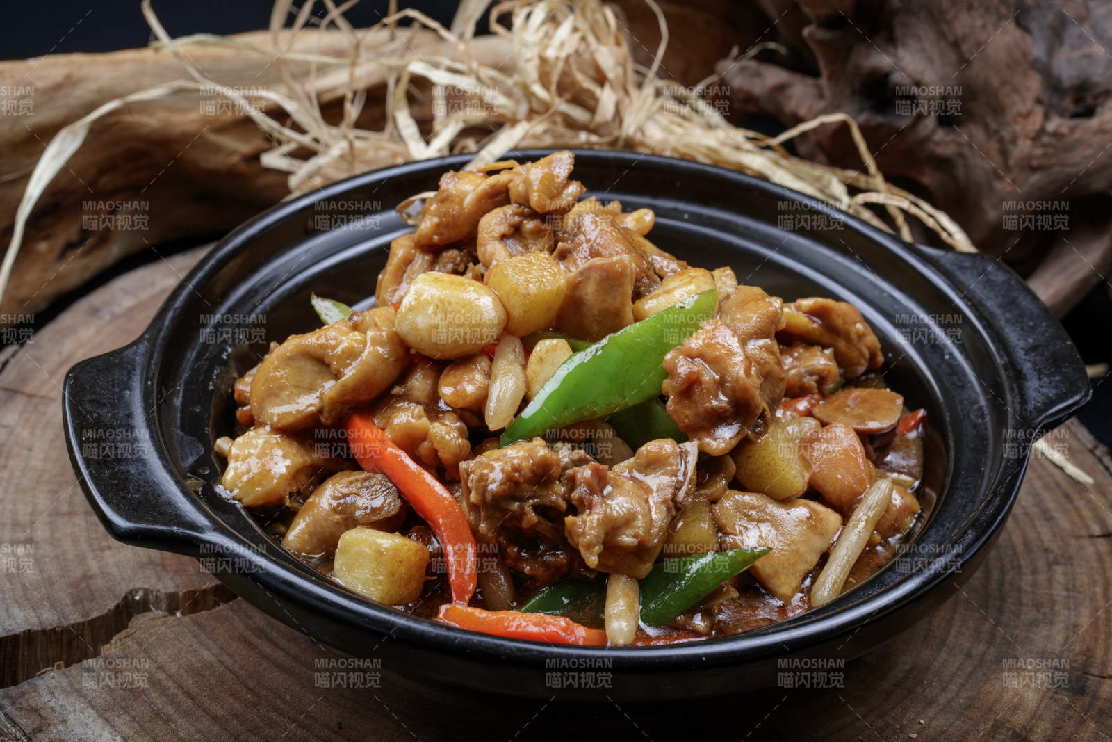 黑色砂锅装的砂锅蒜香鸡摆放在樟木砧板上