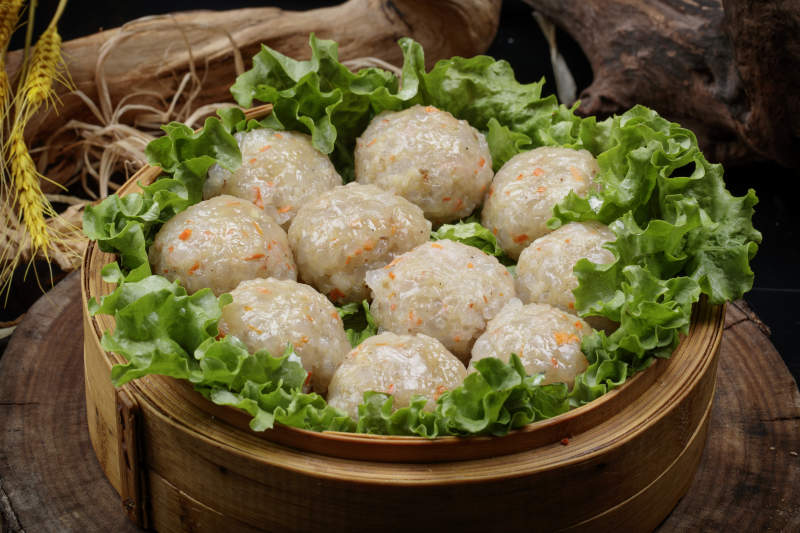 笼屉装的粉蒸土豆大丸子摆放在樟木砧板上