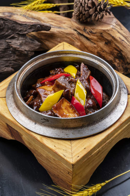 木托鐵鍋裝的醬爆牛仔骨擺放在黑色背景上