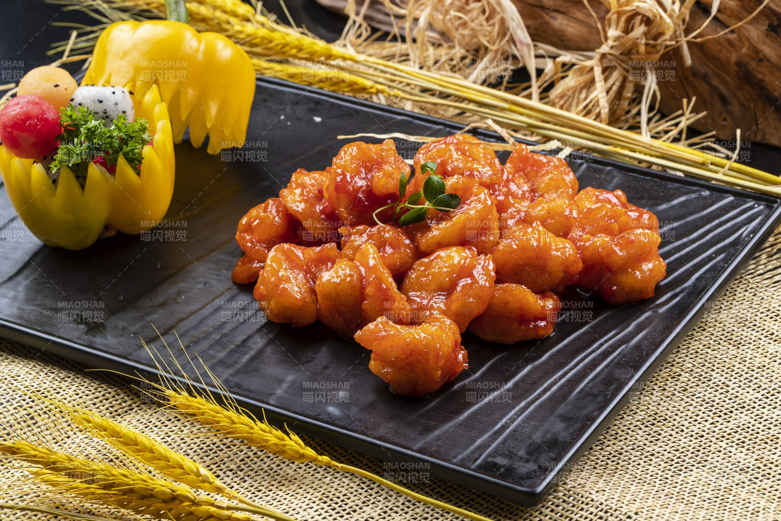 黑色石盘装的宫爆大虾球摆放在麻布垫子上