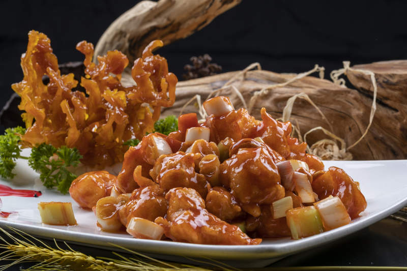 造型奇特的的宫保大虾球摆放在黑色背景上