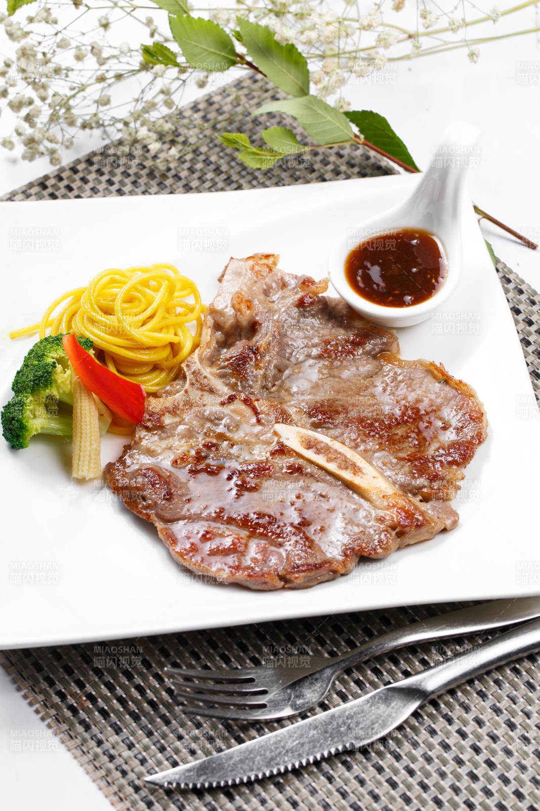 方形瓷盤裝的新西蘭T骨牛排擺放在餐墊上