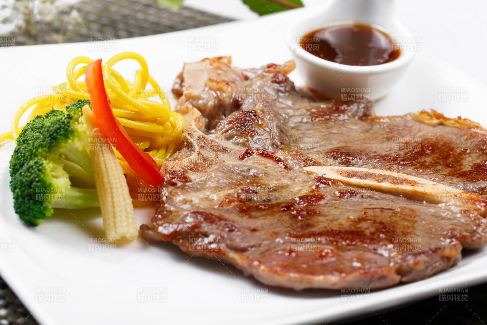 方形瓷盘装的新西兰T骨牛排摆放在餐垫上