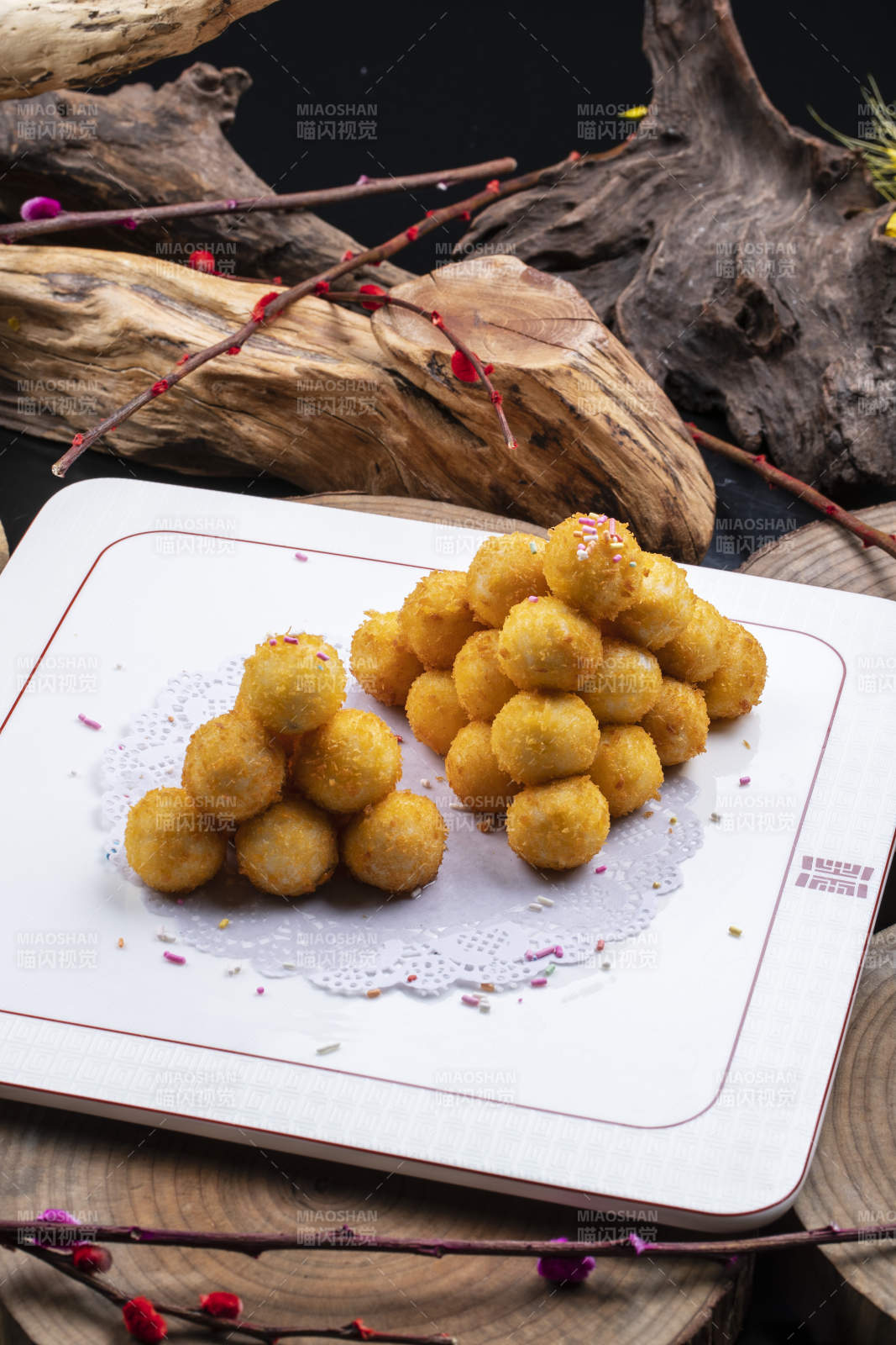 方形瓷盘装的黄金炸汤圆摆放在樟木砧板上