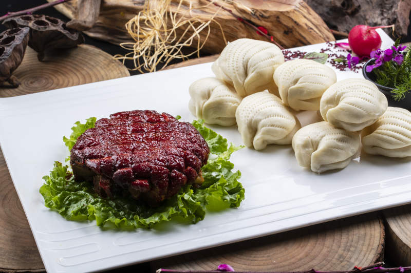 长方形瓷盘装的花馍夹酱肉摆放在樟木砧板上