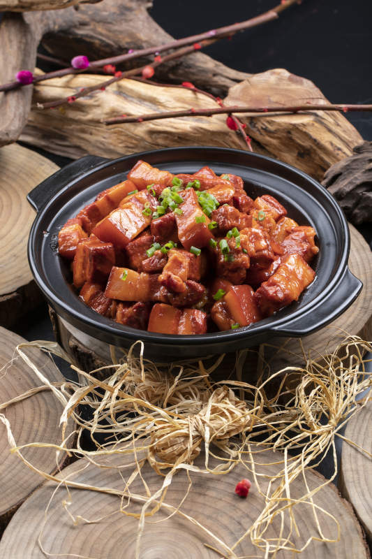 黑色砂锅装的锅仔红烧肉摆放在樟木砧板上