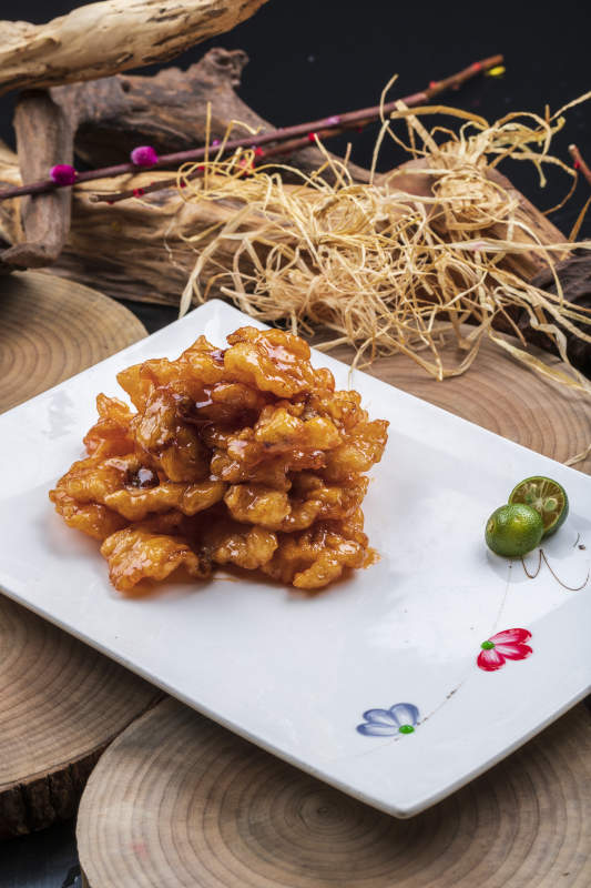 长方形瓷盘装的糖醋龙利鱼摆放在樟木砧板上