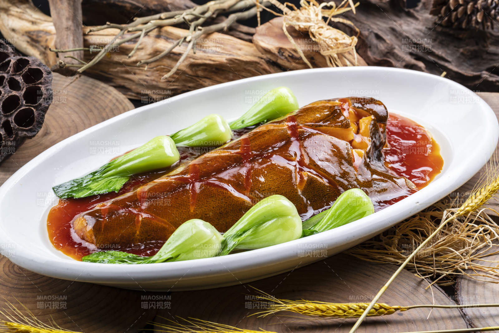 椭圆瓷盘装的红烧鲽鱼尾摆放在樟木砧板上