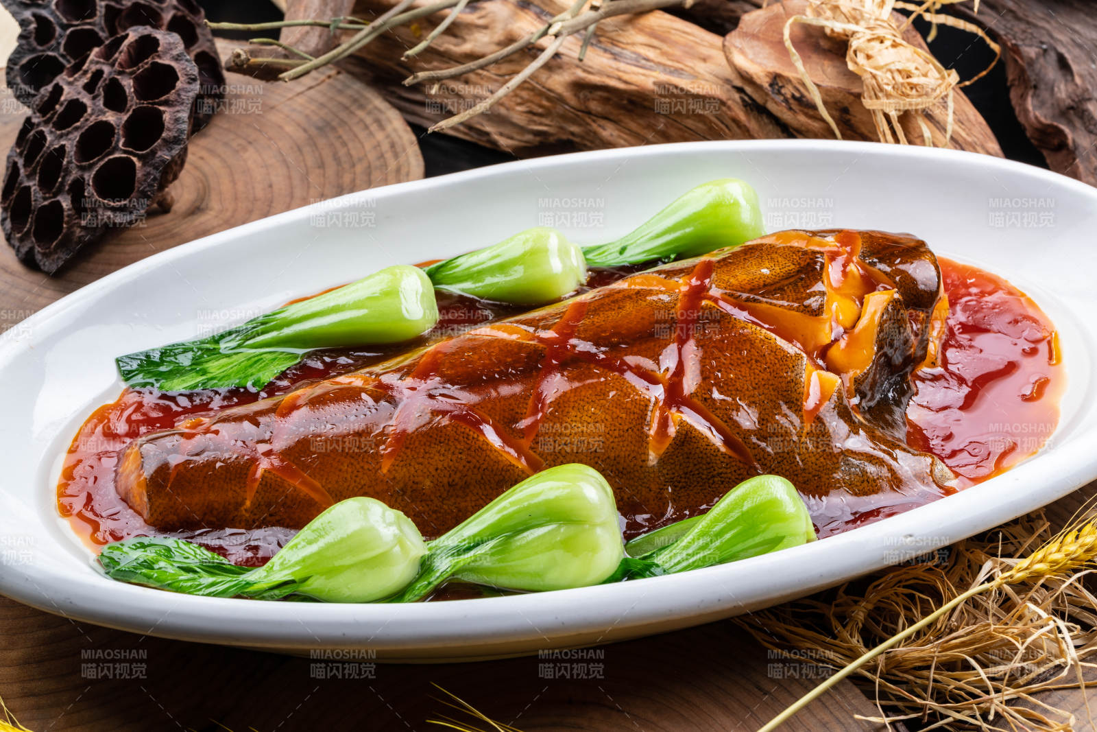 橢圓瓷盤裝的紅燒鰈魚尾擺放在樟木砧板上