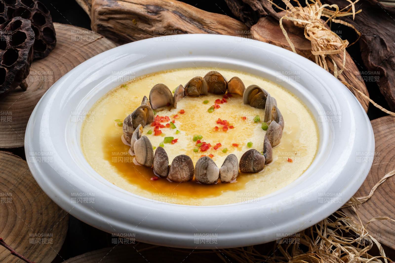 白色圓盤裝的花蛤蒸蛋擺放在樟木砧板上