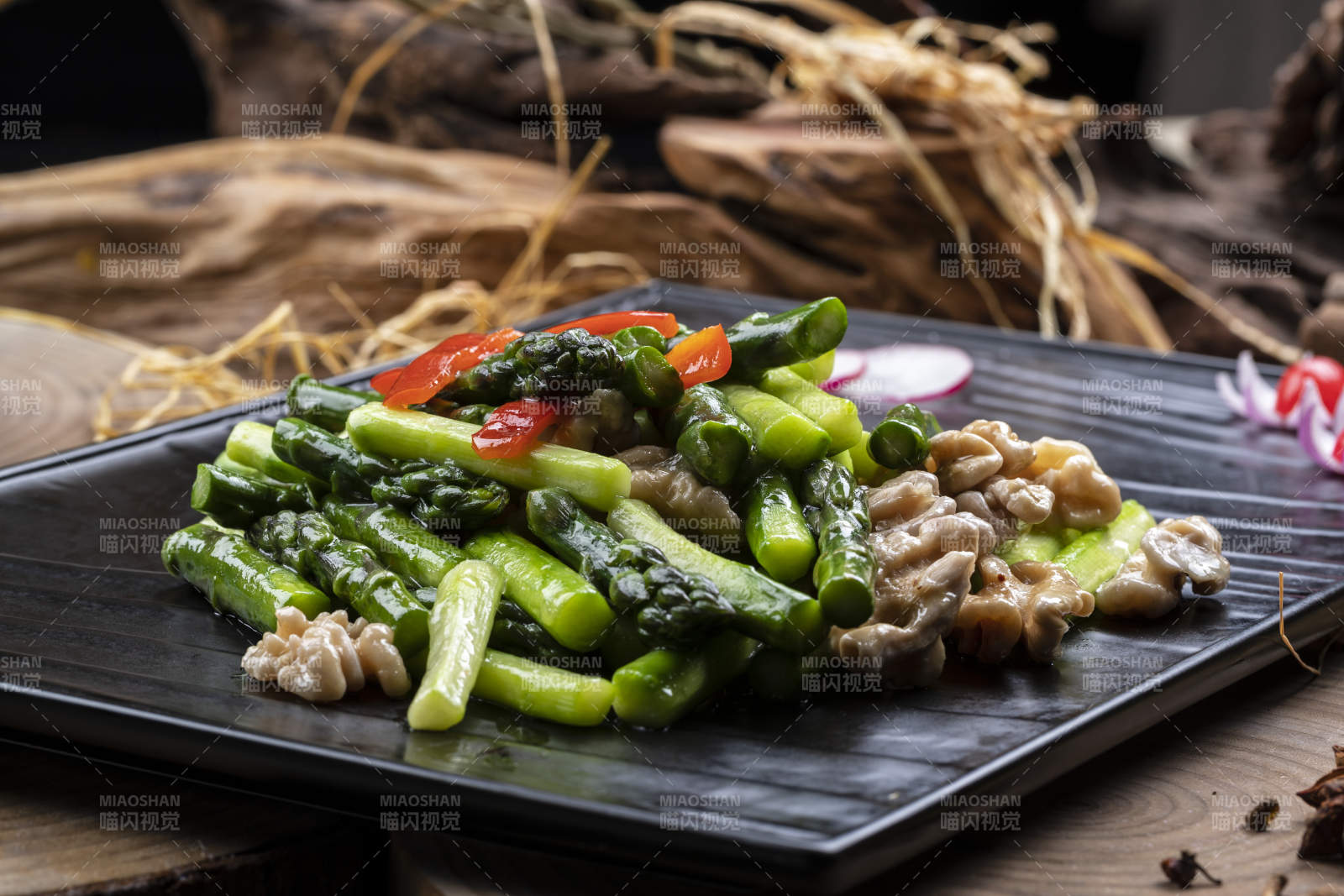 黑色石盘装的鲜芦笋桃仁摆放在樟木砧板上