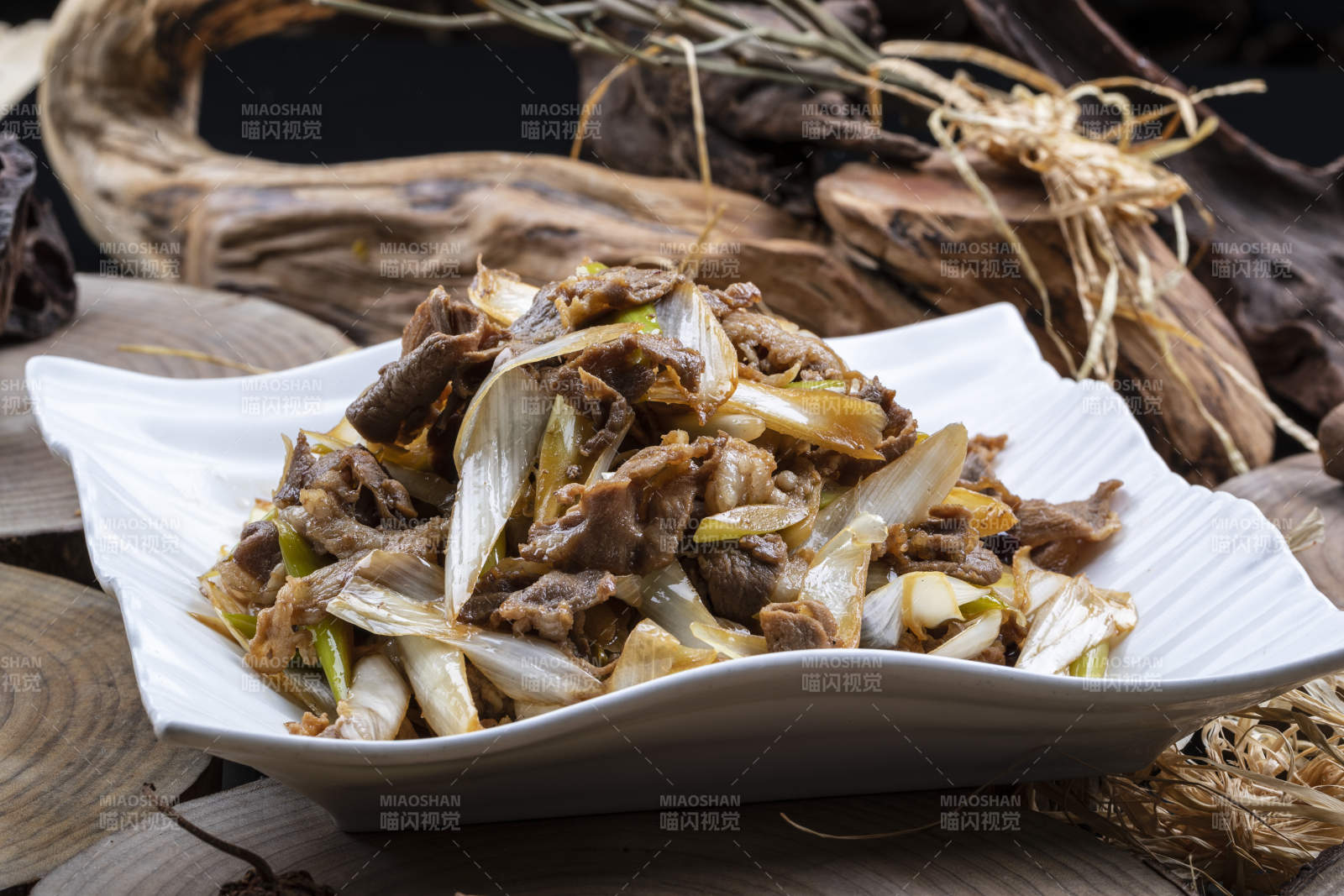 方形花瓷盘装的大葱爆羊肉摆放在樟木砧板上