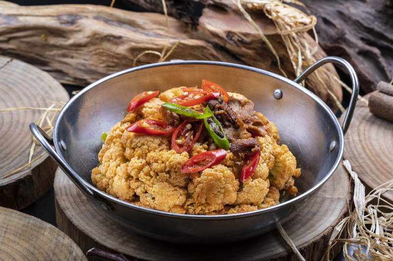 鐵鍋裝的鍋仔有機花菜擺放在樟木砧板上