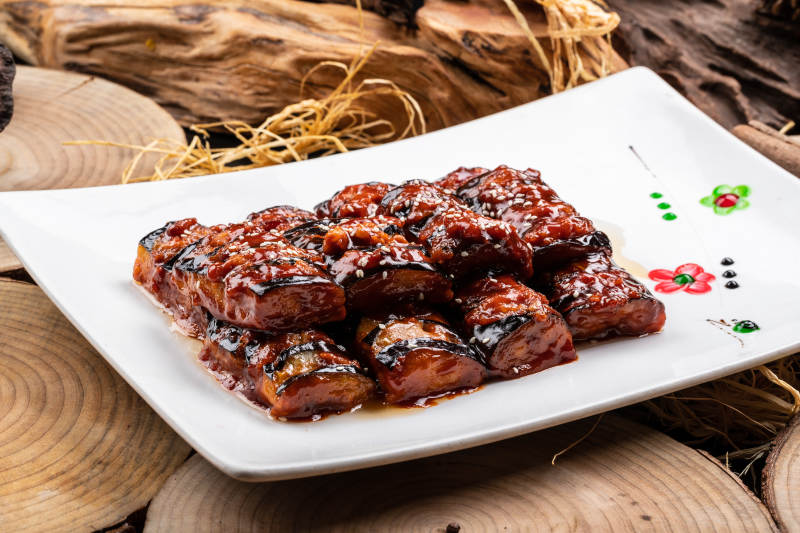 油煎肉末酱茄子摆放在樟木砧板上