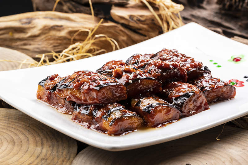 油煎肉末酱茄子摆放在樟木砧板上