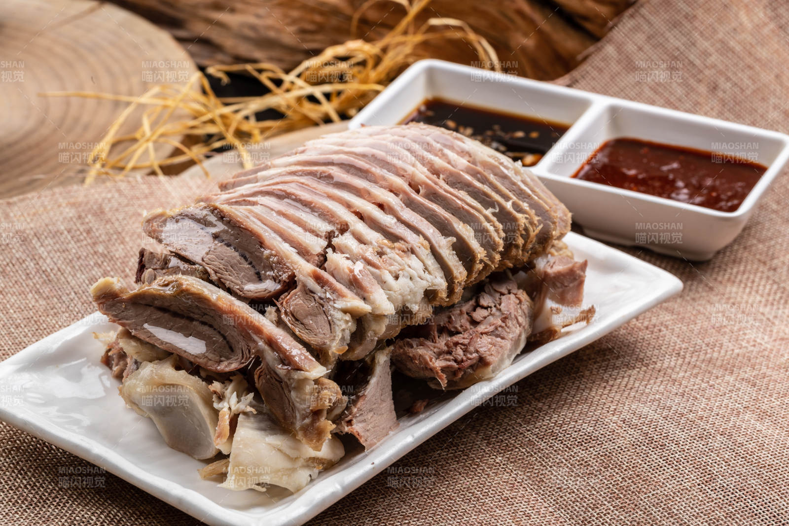 長方形瓷盤裝的白灼羊背擺放在麻布墊子上