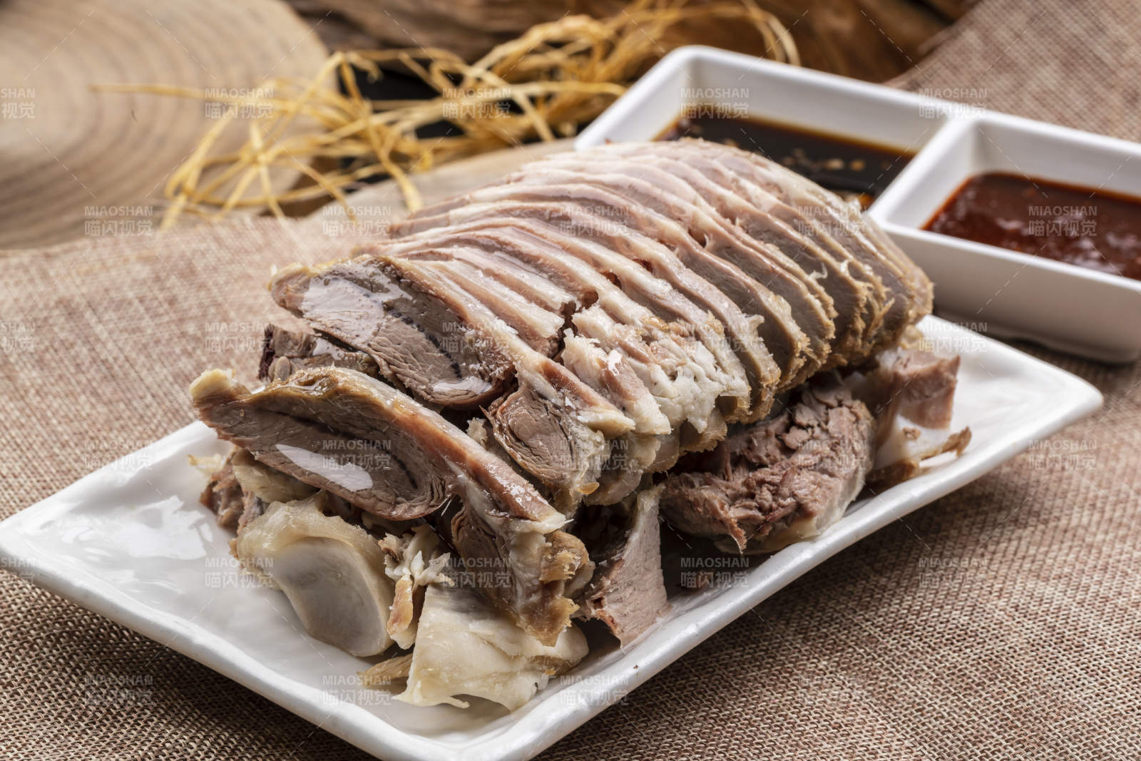 長方形瓷盤裝的白灼羊背擺放在麻布墊子上