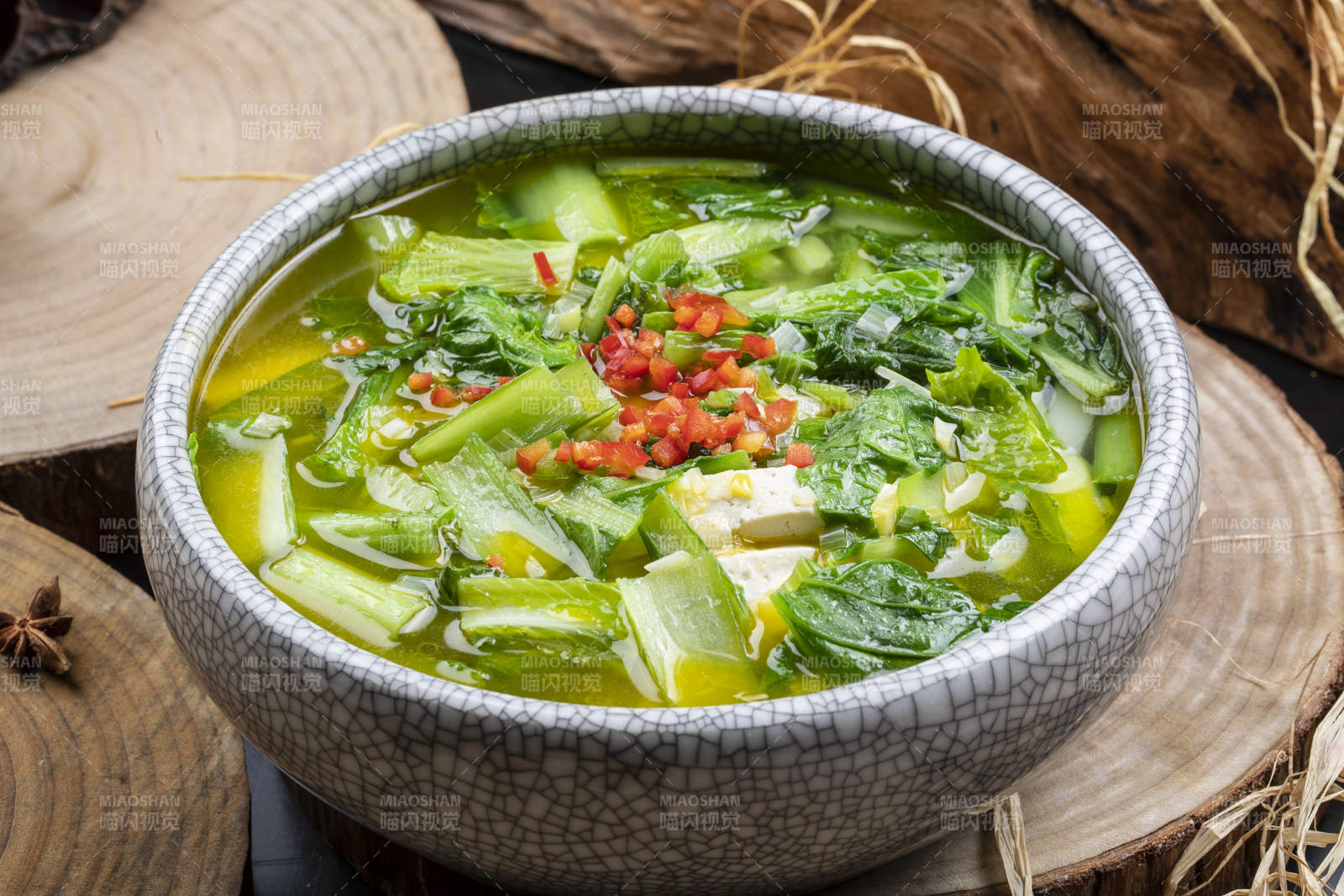 開片瓷碗裝的小白菜燒豆腐擺放在樟木砧板上