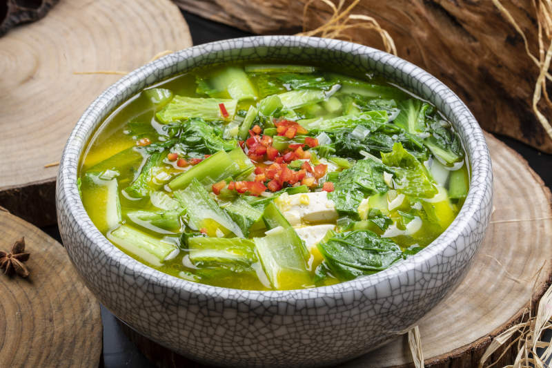 开片瓷碗装的小白菜烧豆腐摆放在樟木砧板上