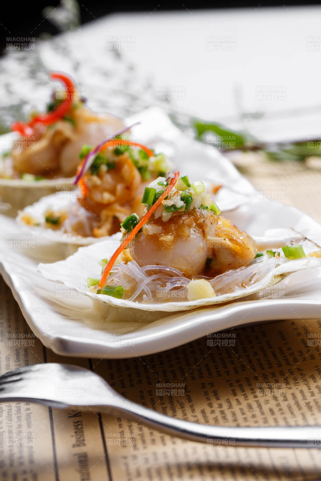 蒜蓉粉絲XO醬蒸扇貝擺放在英文包裝紙上-攝影圖