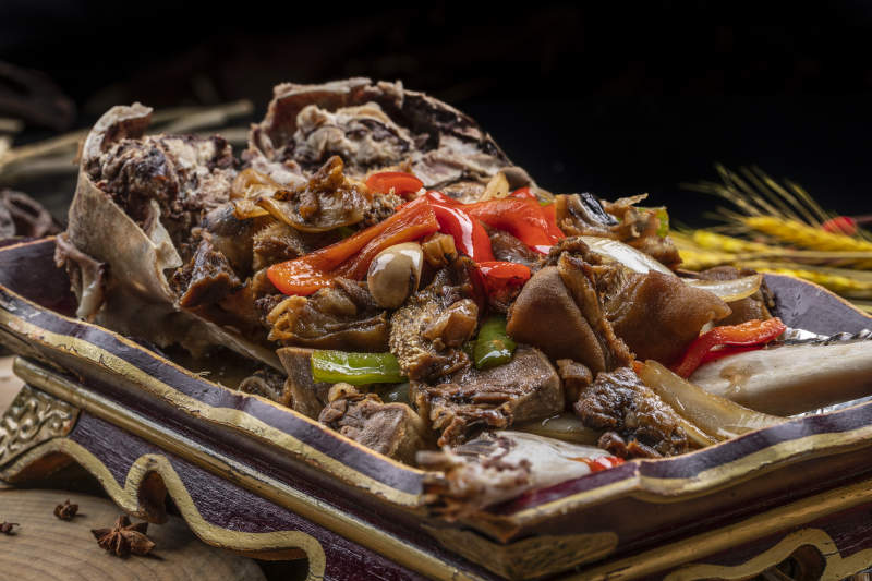 紅漆木盤裝的水煮蒜泥羊頭擺放在樟木砧板上