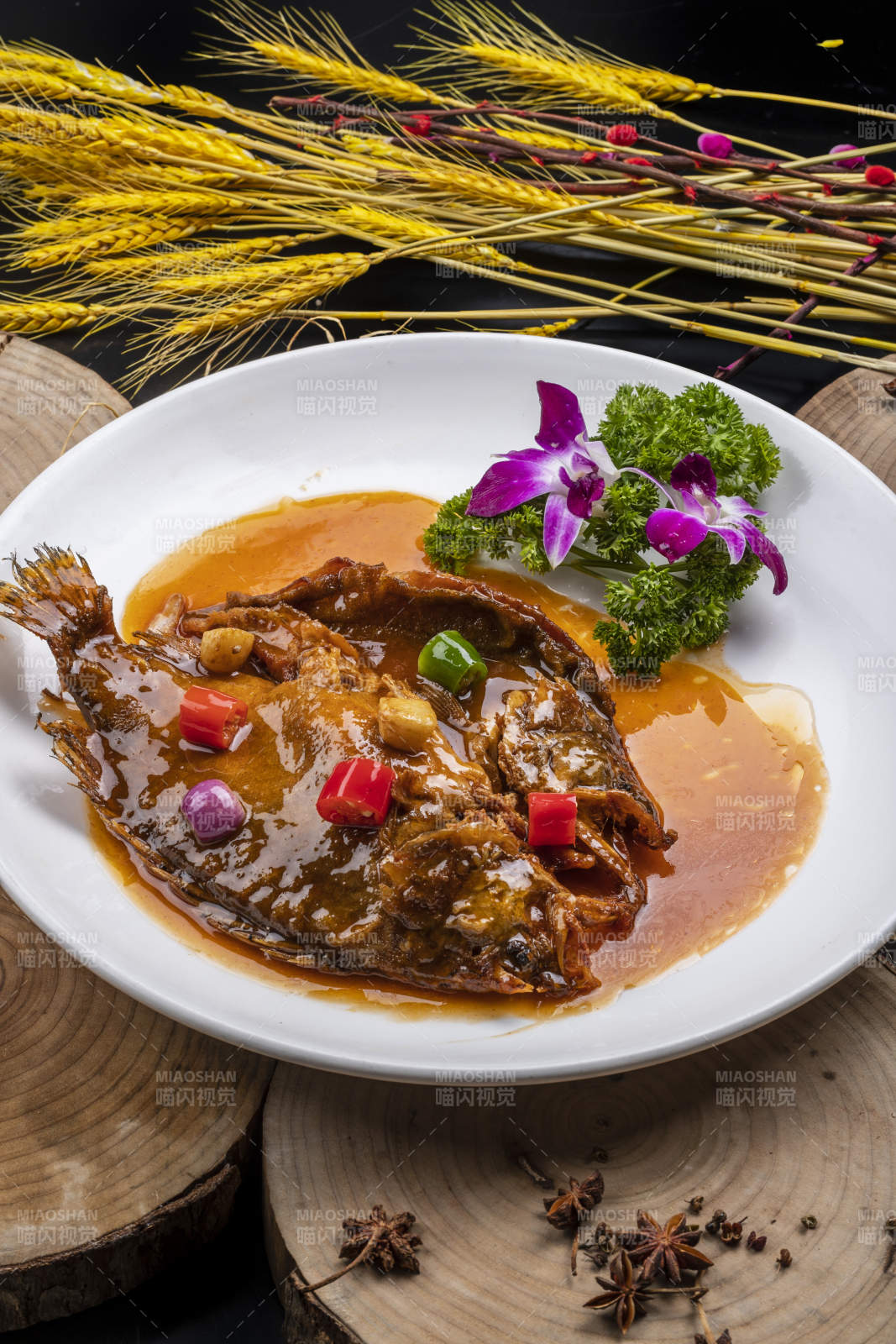 白色圓盤裝的紅燒羅非魚擺放在樟木砧板上